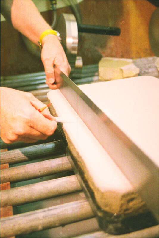 Wayne uses a metal tear bar, or straight edge, to verify that the surface of the stone is even. ...