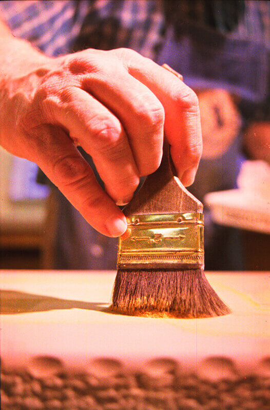 Rosin is hand-brushed over the wax images on the surface of the stone.